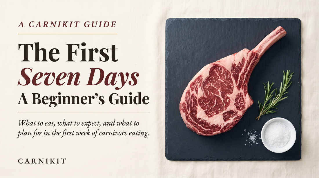 Editorial overhead photograph of a raw bone-in tomahawk ribeye on a dark slate board with a sprig of rosemary and a small bowl of flaked sea salt, on a cream linen background — the cover image for Carnikit's 7-day carnivore diet beginner's guide.